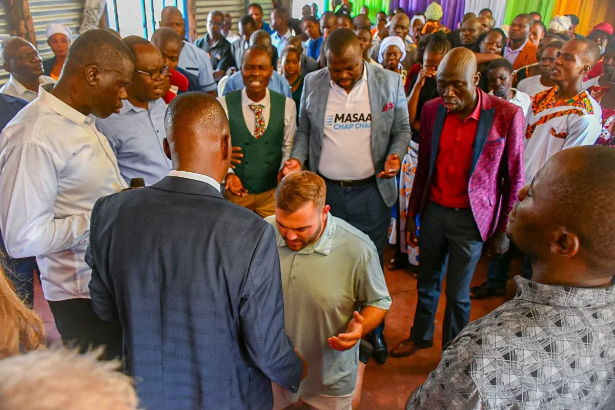 Church members gathered in prayer around Trevor during a service in Kenya